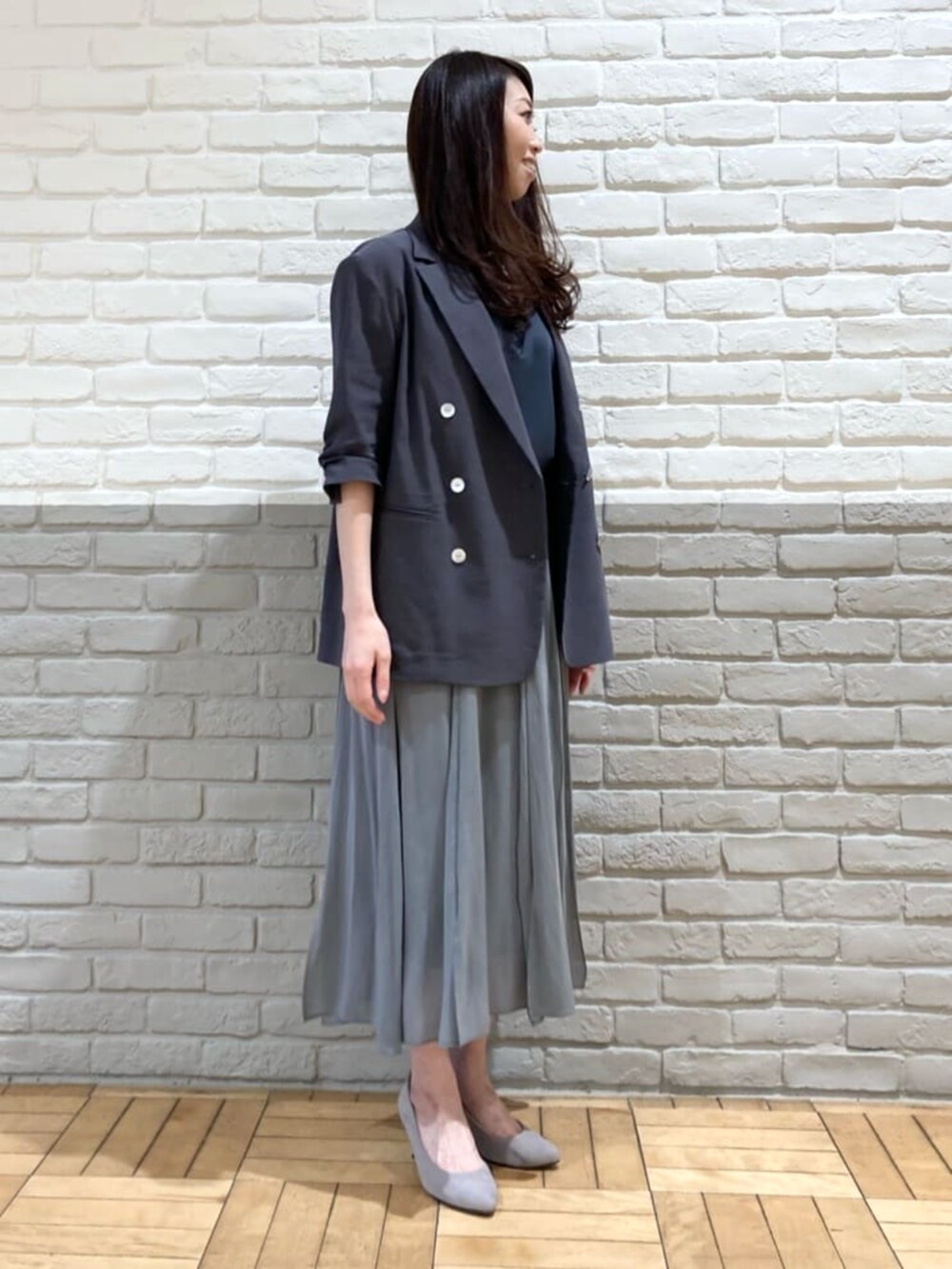 グレー系のテーラードジャケット、グリーン系のスカート、ブラック系のタンクトップを着用したレディースの春コーディネートの4枚目の写真