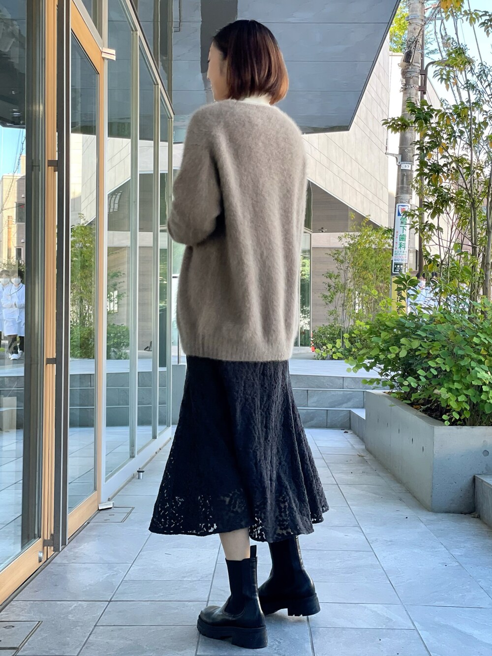 ブラウン系のカーディガン/ボレロ、ホワイト系のニット/セーター、ブラック系のスカートを着用したレディースの秋コーディネートの2枚目の写真