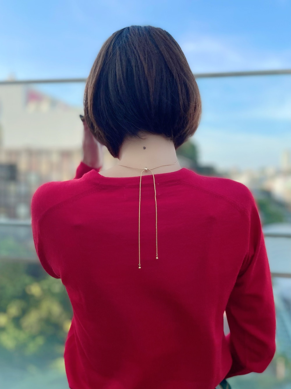 レッド系のニット/セーター、グリーン系のスカート、レッド系のニット/セーターを着用したレディースの秋コーディネートの4枚目の写真