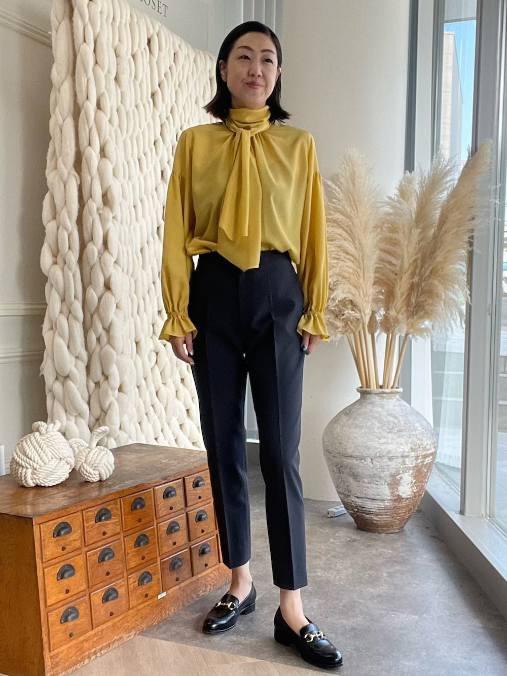 イエロー系のシャツ/ブラウス、ブルー系のカーディガン/ボレロ、グレー系のパンツを着用したレディースの夏コーディネートの2枚目の写真