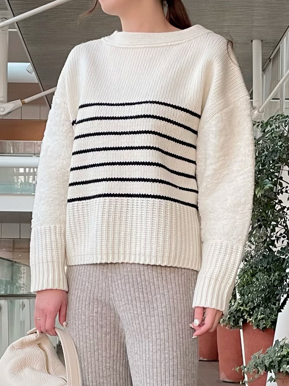 ホワイト系のニット/セーター、ベージュ系のパンツ、ホワイト系のバッグを着用したレディースの冬コーディネートの2枚目の写真