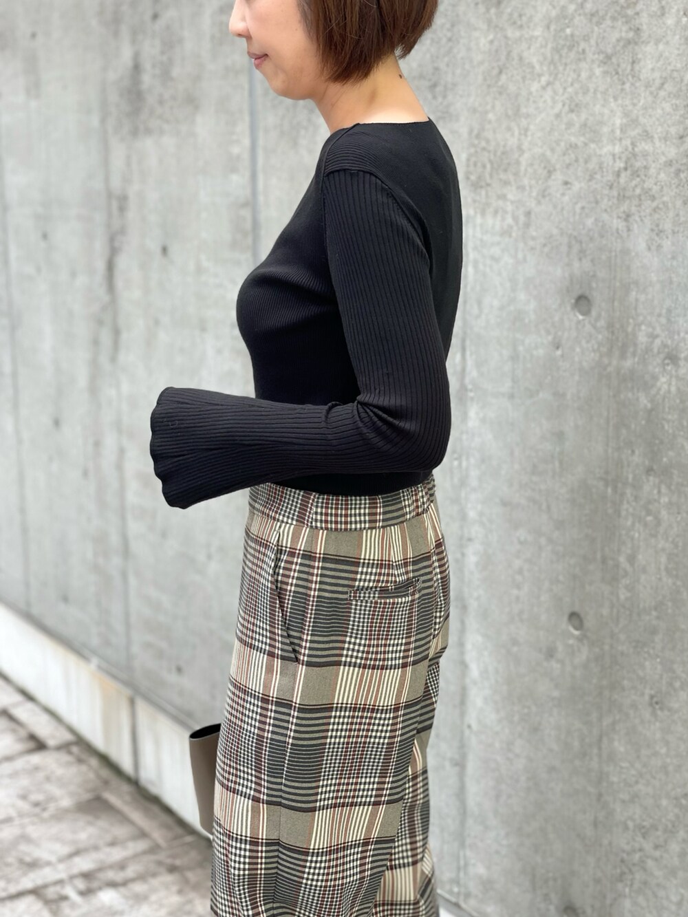 ブラック系のニット/セーター、ベージュ系のパンツ、ブラック系のTシャツ/カットソーを着用したレディースの秋コーディネートの3枚目の写真