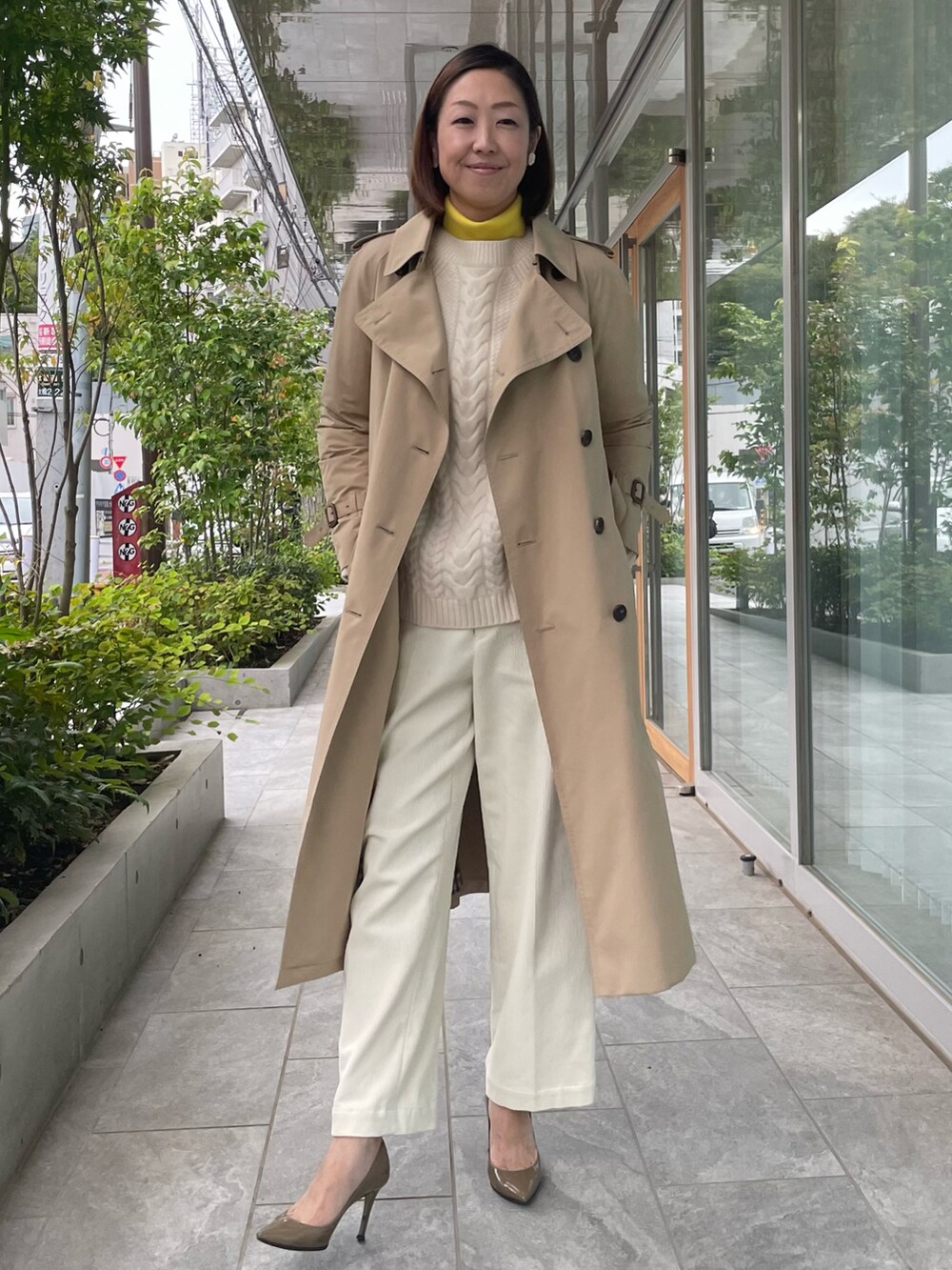 ベージュ系のトレンチコートを着用したレディースの秋コーディネートの2枚目の写真