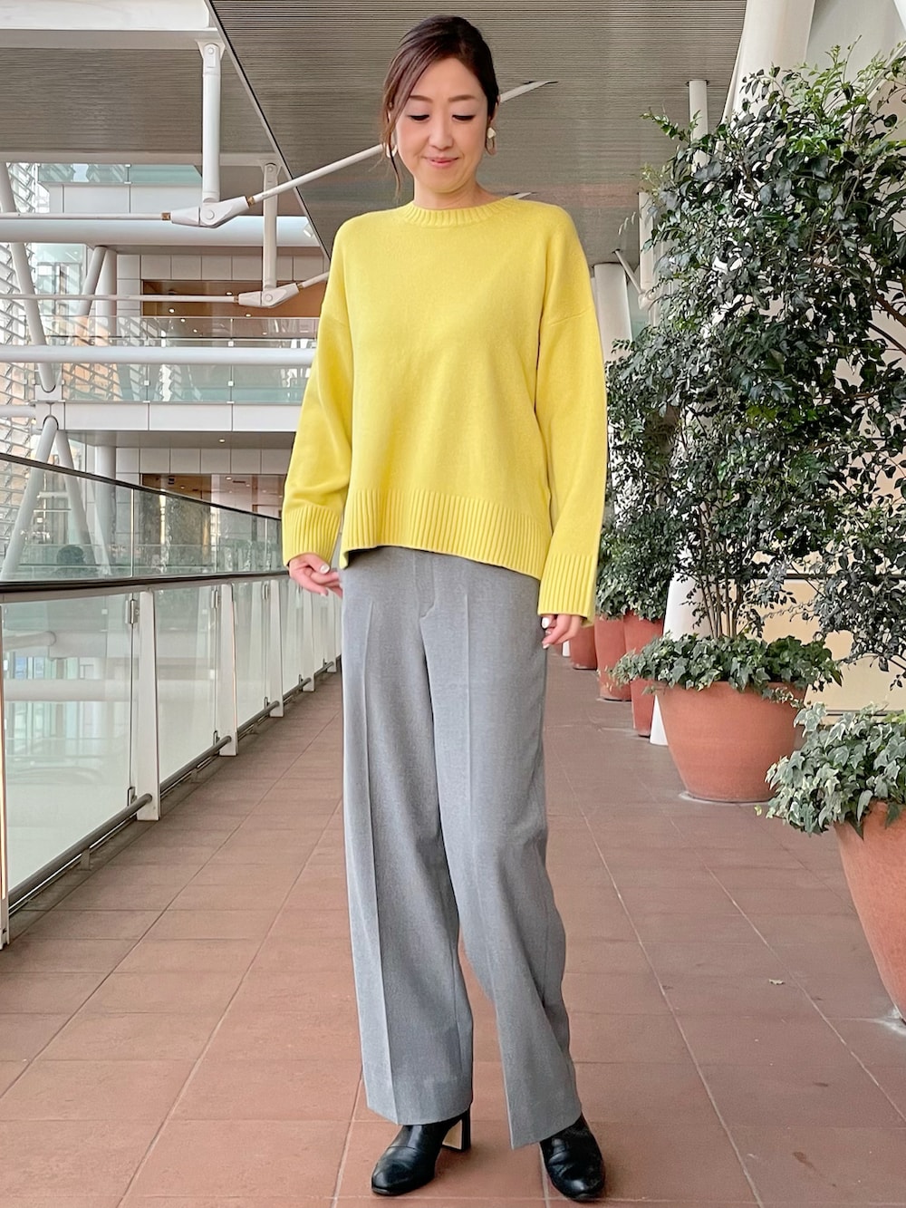 イエロー系のニット/セーター、グレー系のパンツ、グレー系のその他パンツを着用したレディースの冬コーディネートの2枚目の写真