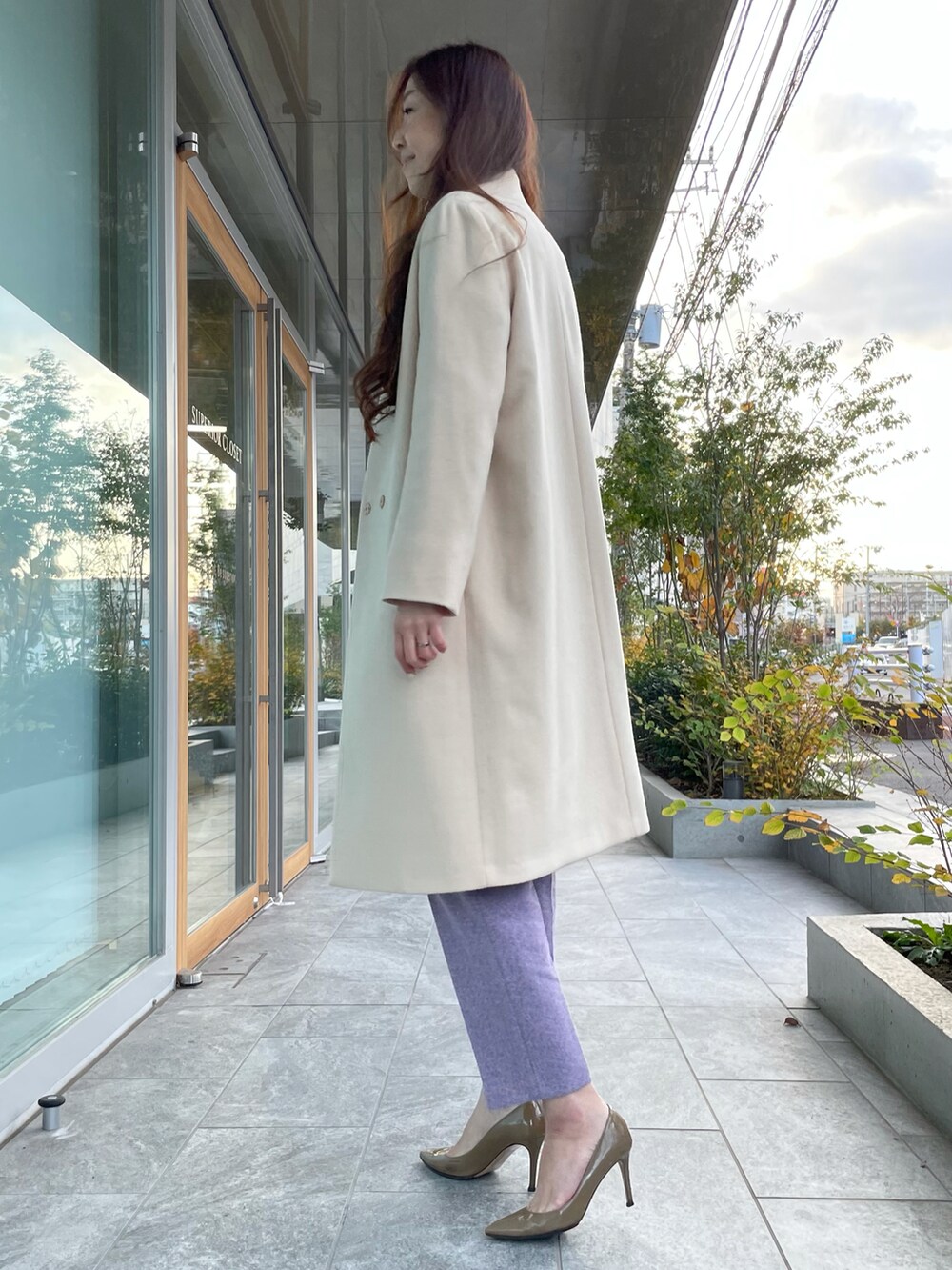 ホワイト系のニット/セーター、ベージュ系のノーカラーコート、パープル系のパンツを着用したレディースの冬コーディネートの2枚目の写真