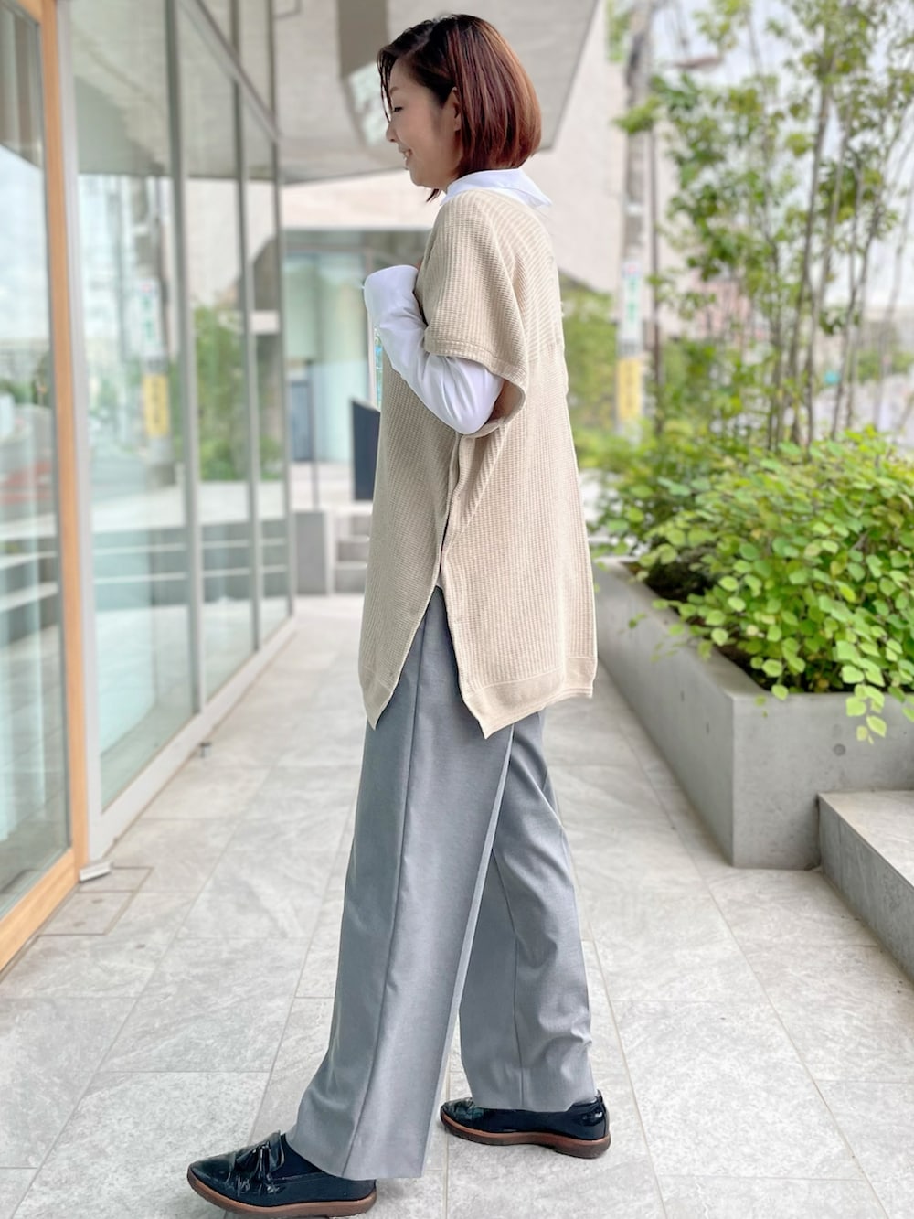 ベージュ系のトップス、ホワイト系のシャツ/ブラウス、グレー系のパンツを着用したレディースの秋コーディネートの5枚目の写真