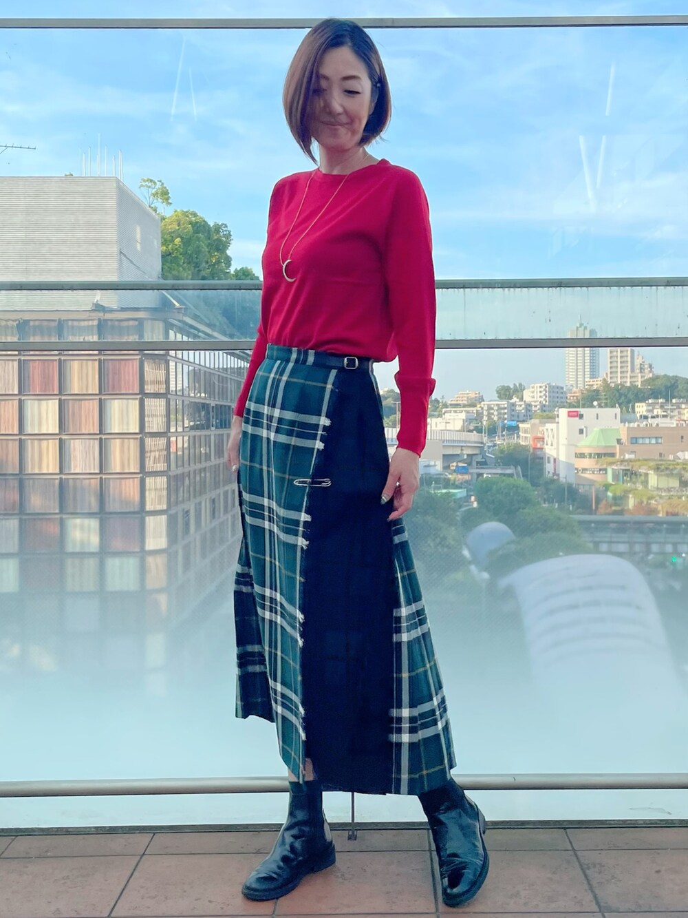 レッド系のニット/セーター、グリーン系のスカート、レッド系のニット/セーターを着用したレディースの秋コーディネートの2枚目の写真