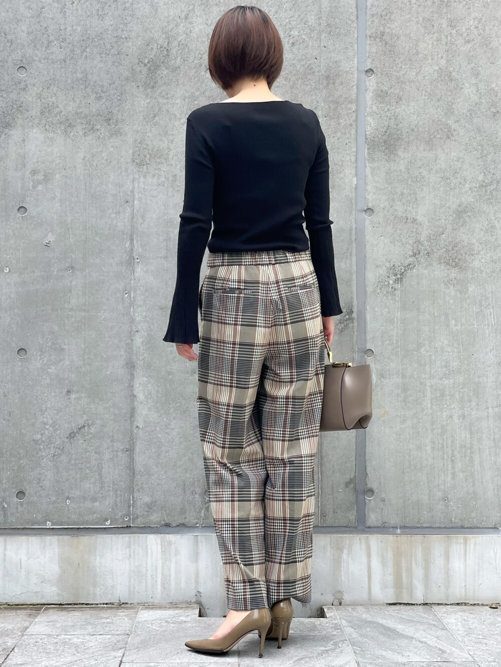 ブラック系のニット/セーター、ベージュ系のパンツ、ブラック系のTシャツ/カットソーを着用したレディースの秋コーディネートの2枚目の写真
