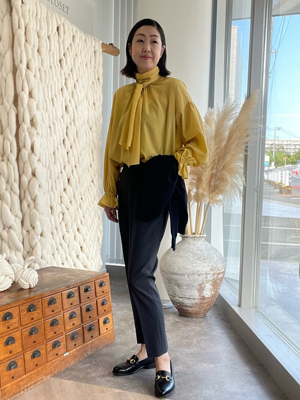 イエロー系のシャツ/ブラウス、ブルー系のカーディガン/ボレロ、グレー系のパンツを着用したレディースの夏コーディネートの3枚目の写真