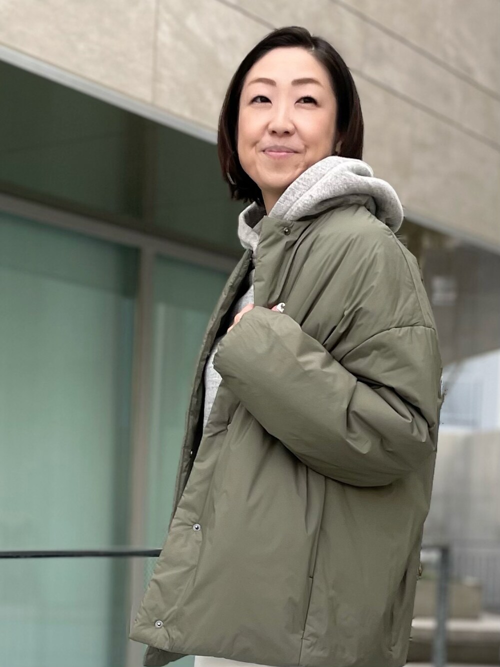 グレー系のパーカー、グリーン系のジャケット/アウター、ホワイト系のデニムパンツを着用したレディースの冬コーディネートの2枚目の写真