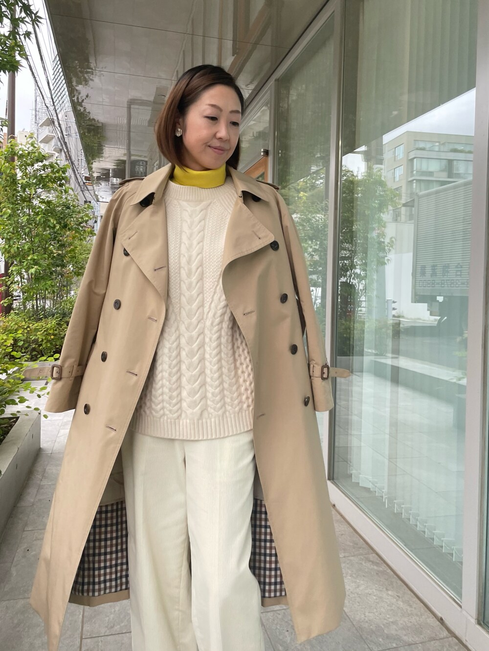 ベージュ系のトレンチコートを着用したレディースの秋コーディネートの3枚目の写真