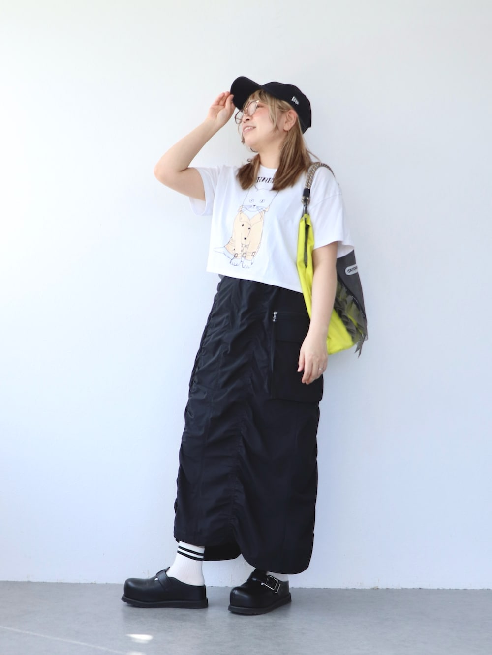 ブラック系のスカート、グレー系のトートバッグ、ホワイト系のTシャツ/カットソーを着用したレディースの春コーディネートの2枚目の写真