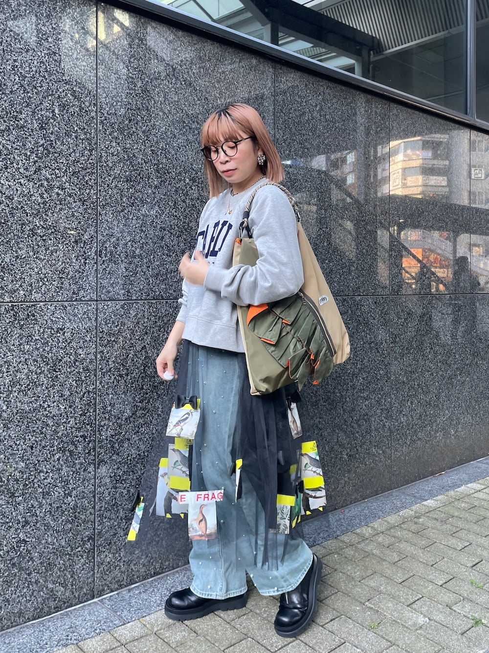 グレー系のスウェット、ブルー系のデニムパンツ、グリーン系のトートバッグを着用したレディースの冬コーディネートの5枚目の写真