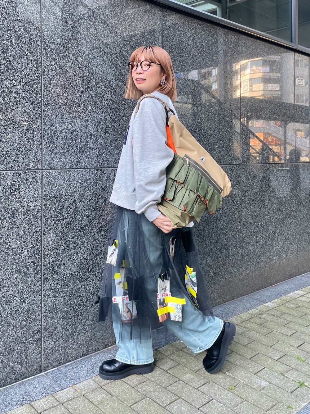 グレー系のスウェット、ブルー系のデニムパンツ、グリーン系のトートバッグを着用したレディースの冬コーディネートの2枚目の写真