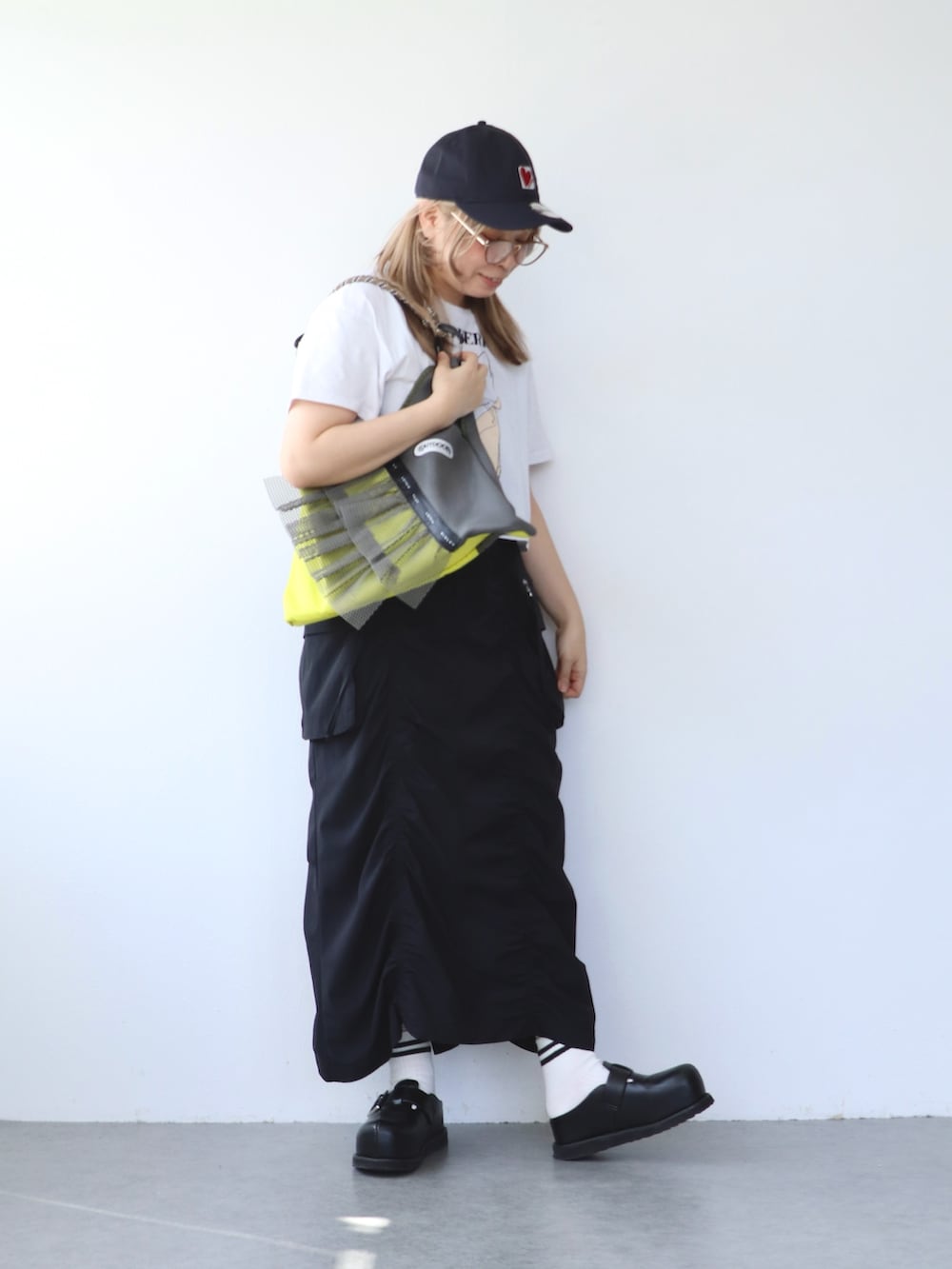 ブラック系のスカート、グレー系のトートバッグ、ホワイト系のTシャツ/カットソーを着用したレディースの春コーディネートの5枚目の写真