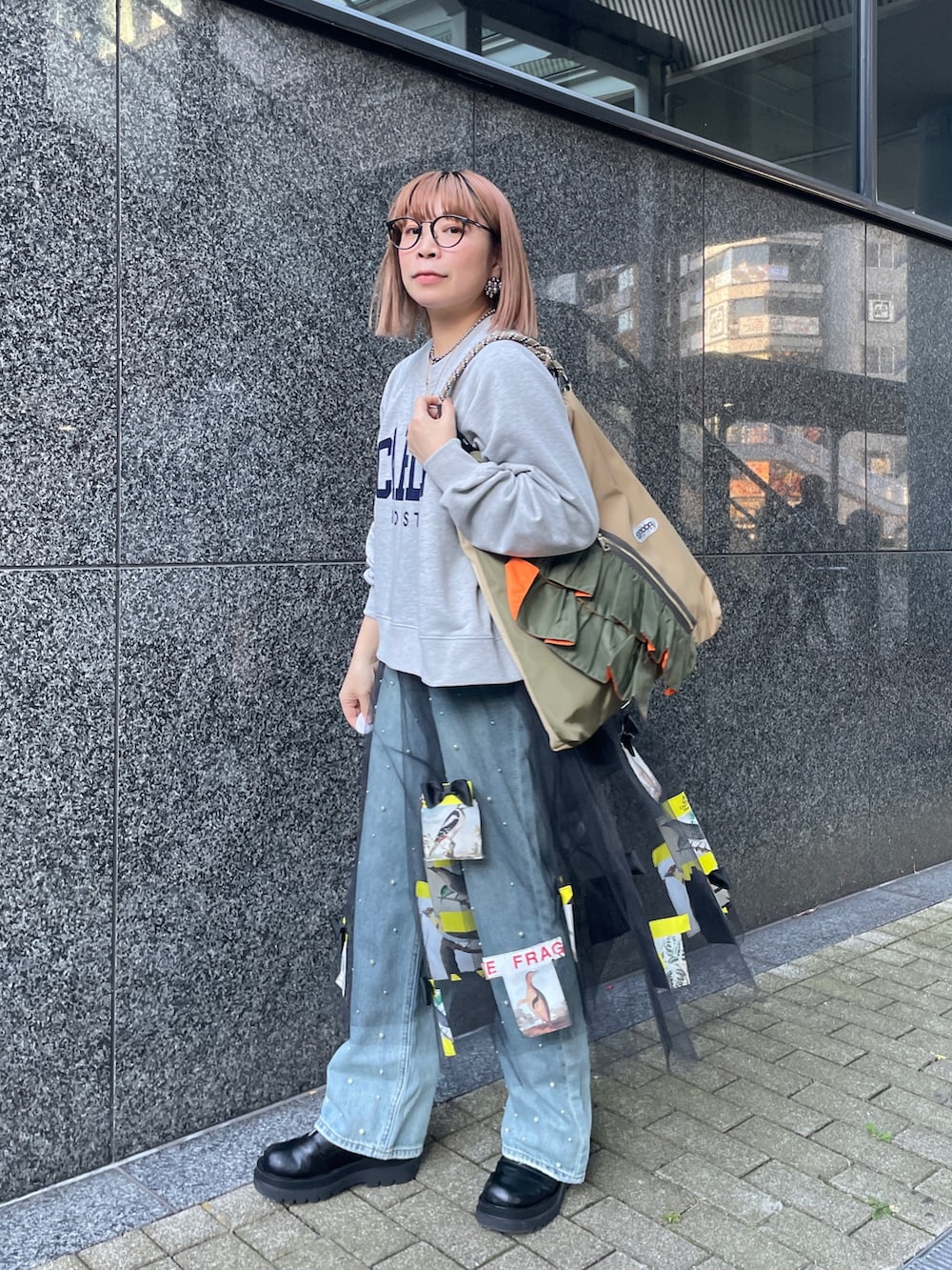 グレー系のスウェット、ブルー系のデニムパンツ、グリーン系のトートバッグを着用したレディースの冬コーディネートの4枚目の写真