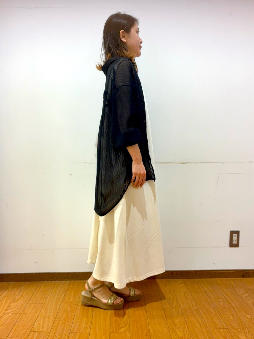 ベージュ系のサンダル、ブラック系のショルダーバッグ、ホワイト系のワンピースを着用したレディースの春コーディネートの2枚目の写真