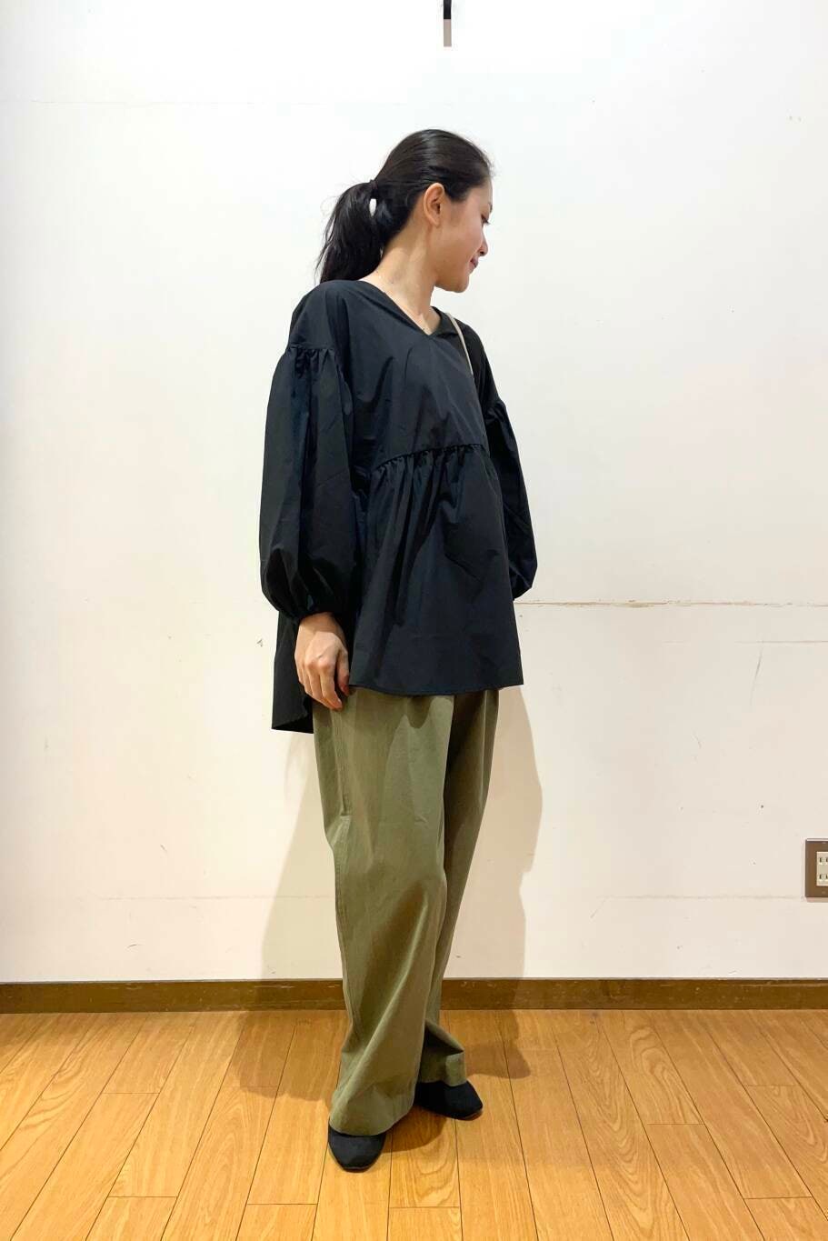 ホワイト系のショルダーバッグ、ブラック系のシャツ/ブラウス、グリーン系のチノパンツを着用したレディースの夏コーディネートの2枚目の写真