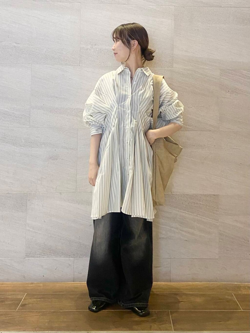 ブラック系のデニムパンツ、ベージュ系のワンピース、ベージュ系のショルダーバッグを着用したレディースの春コーディネートの5枚目の写真