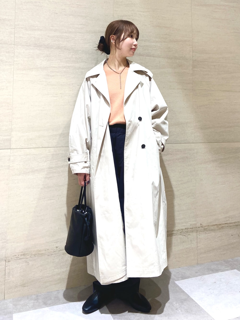 ベージュ系のトレンチコート、ピンク系のニット/セーター、ブラック系のショルダーバッグを着用したレディースの春コーディネートの2枚目の写真