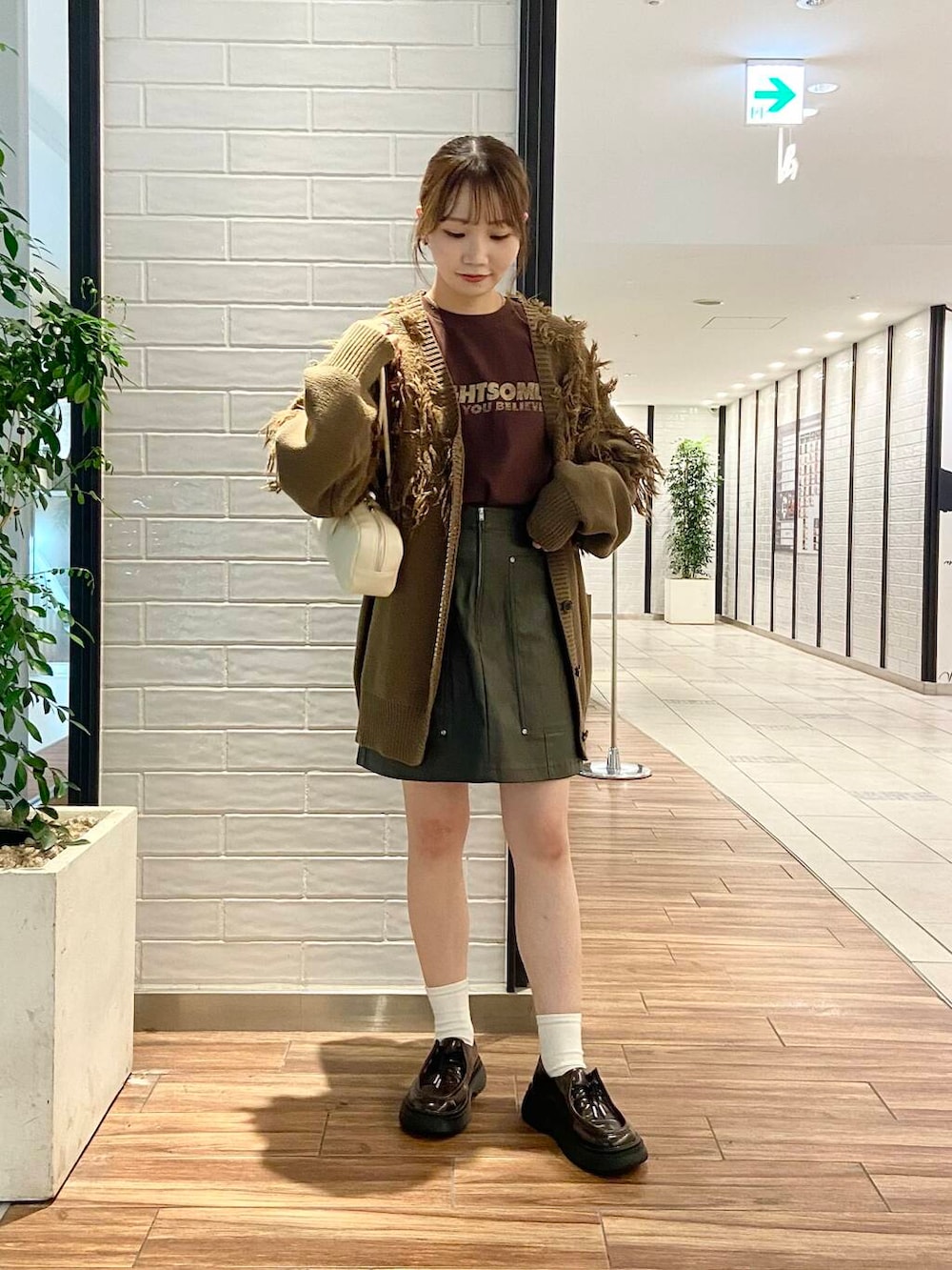 ブラウン系のローファー、グリーン系のカーディガン/ボレロ、ブラウン系のTシャツ/カットソーを着用したレディースの秋コーディネートの2枚目の写真