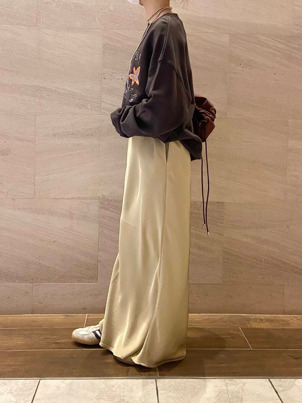 ブラウン系のショルダーバッグ、グレー系のスウェット、ベージュ系のスカートを着用したレディースの冬コーディネートの2枚目の写真