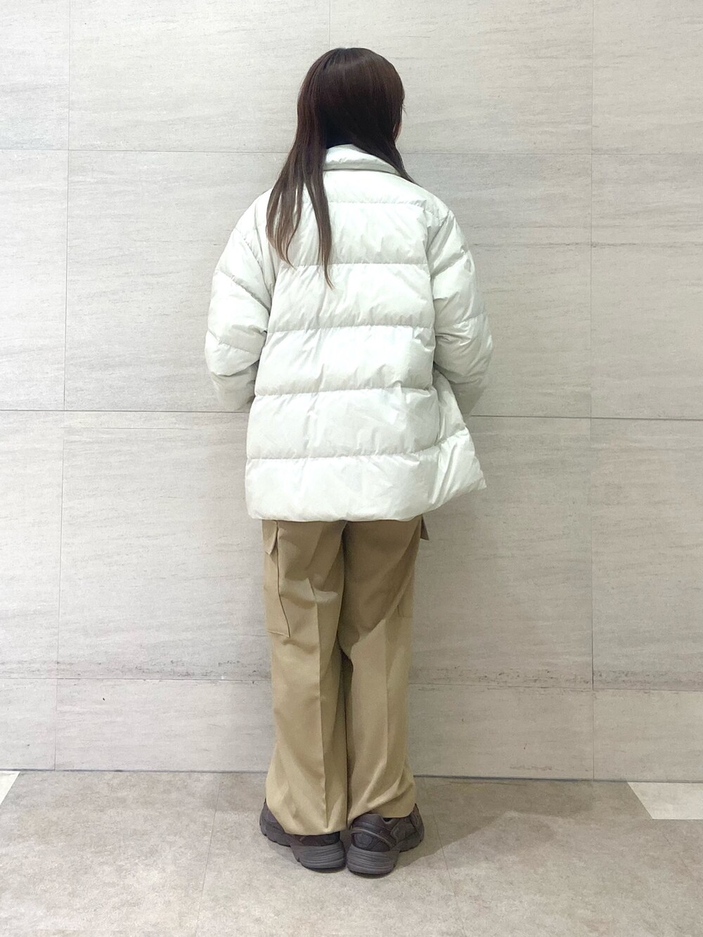 ホワイト系のダウンジャケット/コート、ブラウン系のニット/セーター、ベージュ系のその他パンツを着用したレディースの秋コーディネートの3枚目の写真