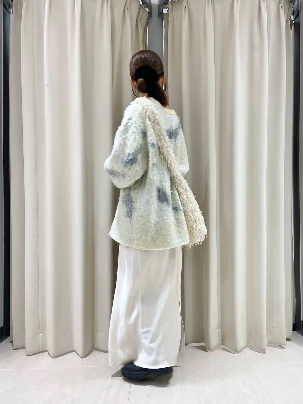 ブラック系のブーツ、ホワイト系のショルダーバッグ、ホワイト系のスカートを着用したレディースの冬コーディネートの3枚目の写真