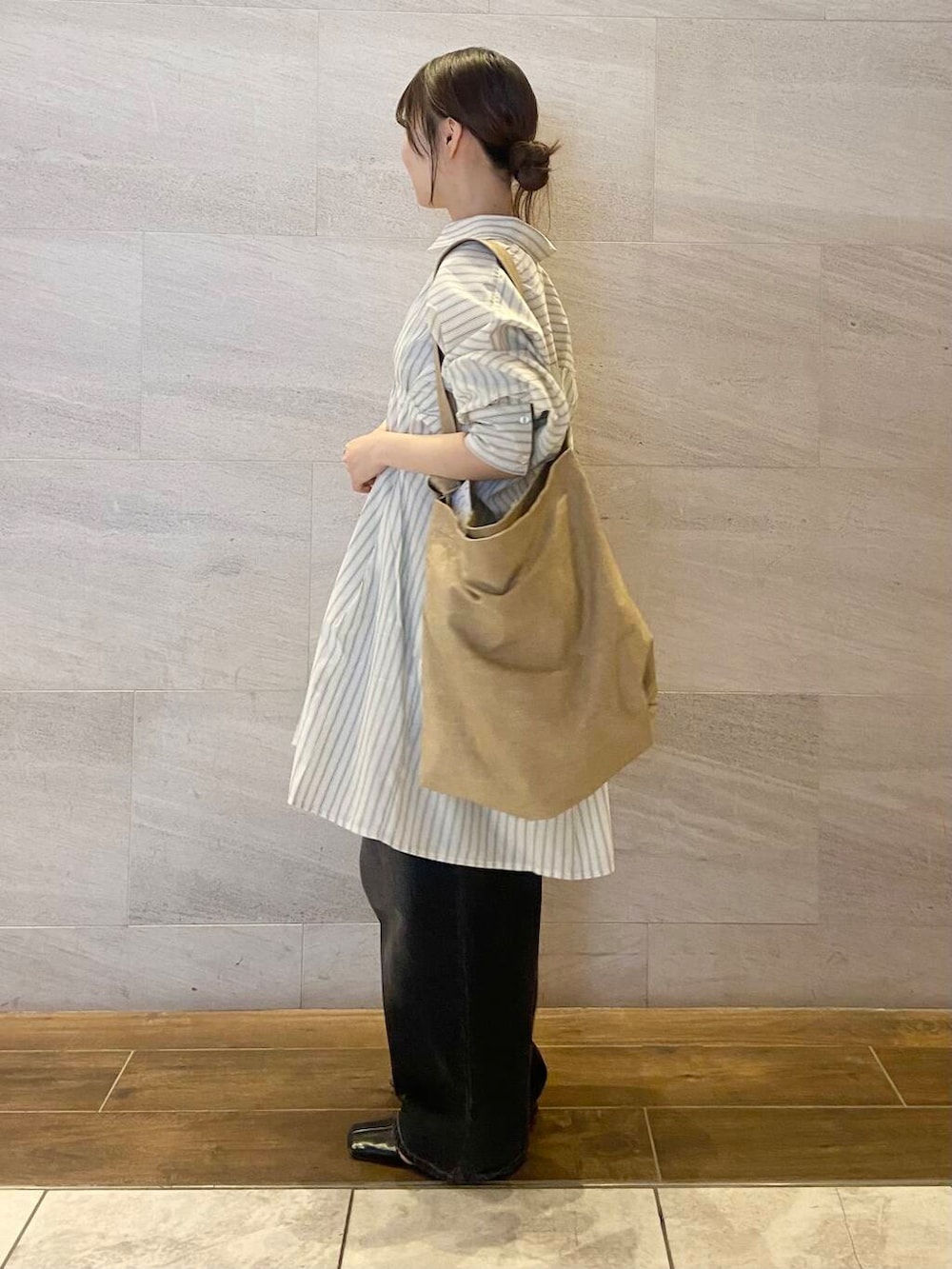 ブラック系のデニムパンツ、ベージュ系のワンピース、ベージュ系のショルダーバッグを着用したレディースの春コーディネートの3枚目の写真