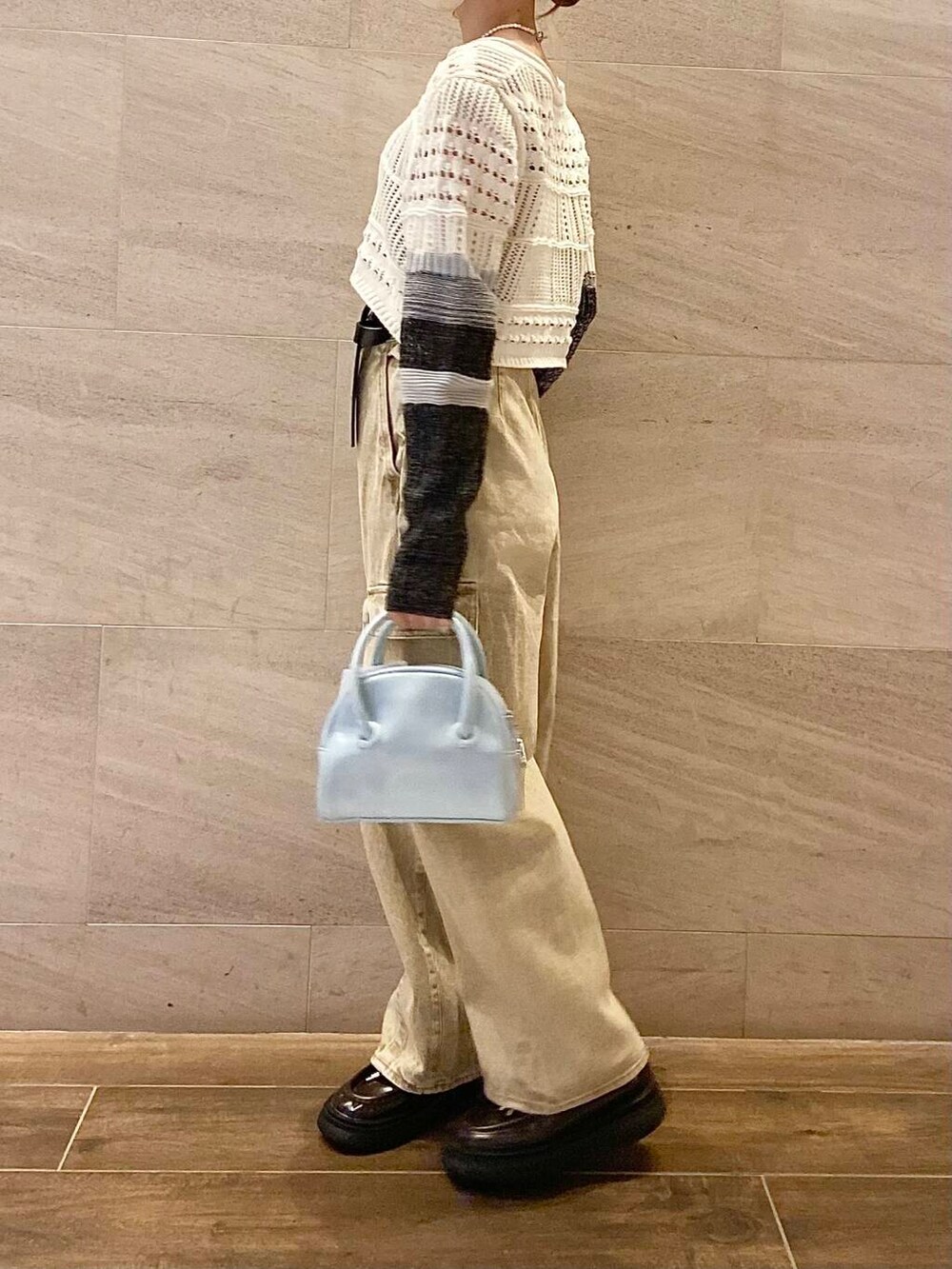 ブルー系のボストンバッグ、ホワイト系のカーディガン/ボレロ、ベージュ系のデニムパンツを着用したレディースの春コーディネートの3枚目の写真