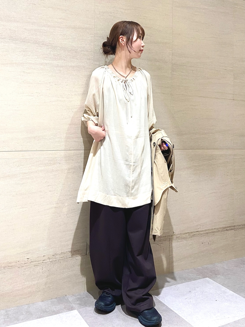 ベージュ系のステンカラーコート、ブラウン系のその他パンツ、ベージュ系のその他トップスを着用したレディースの春コーディネートの3枚目の写真