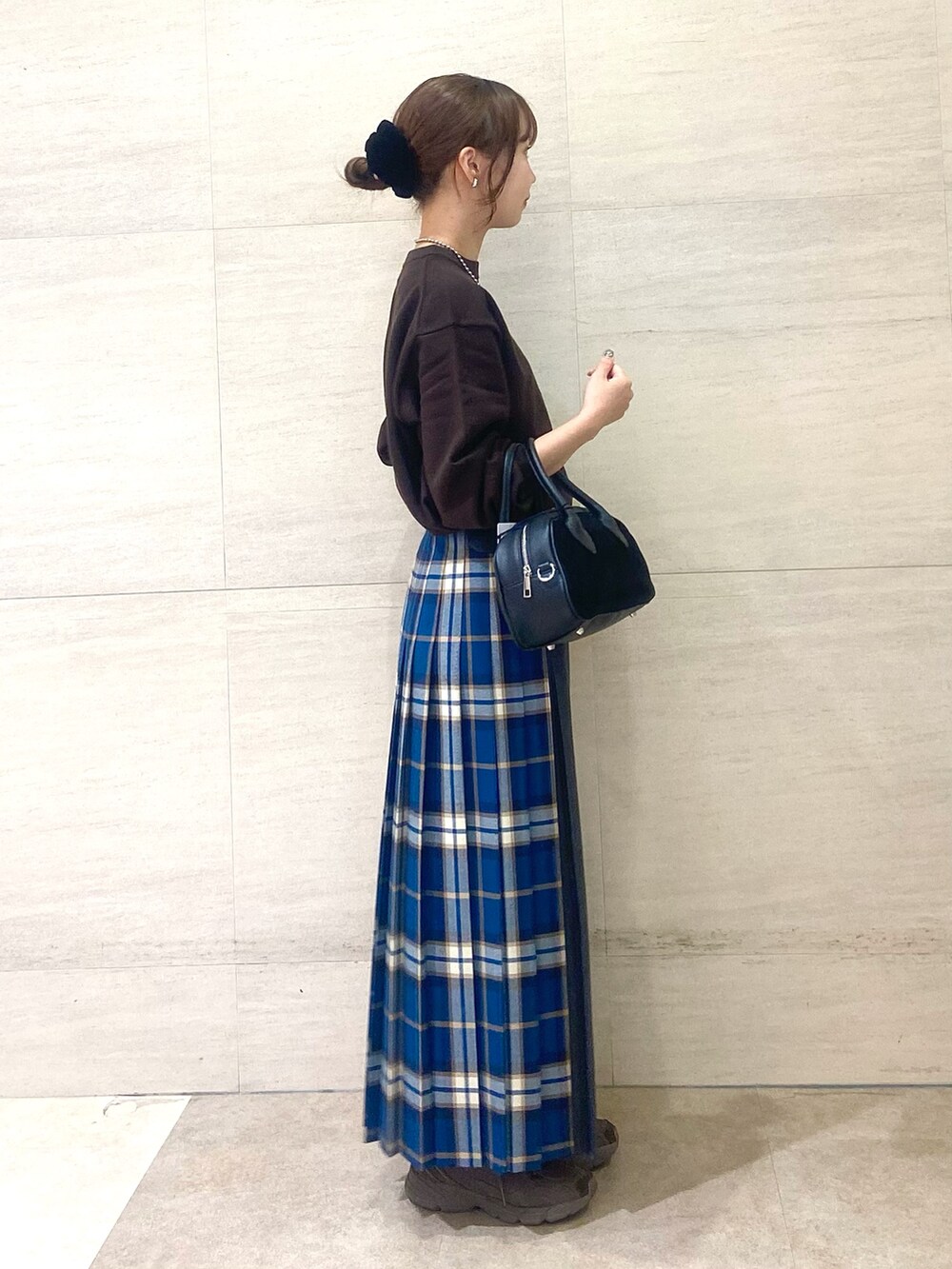 グリーン系のスカート、ブラウン系のニット/セーター、ブラック系のショルダーバッグを着用したレディースの秋コーディネートの2枚目の写真