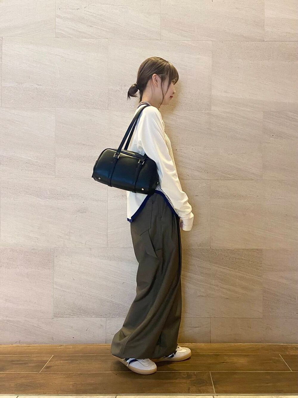 ブラック系のボストンバッグ、グリーン系のスラックス、ホワイト系のTシャツ/カットソーを着用したレディースの秋コーディネートの3枚目の写真