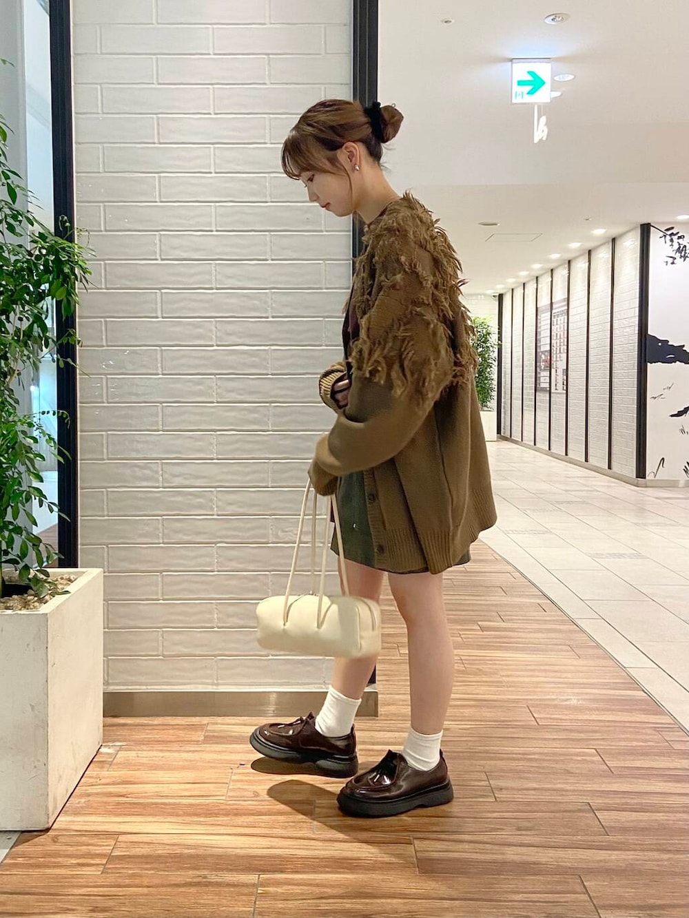 ブラウン系のローファー、グリーン系のカーディガン/ボレロ、ブラウン系のTシャツ/カットソーを着用したレディースの秋コーディネートの3枚目の写真