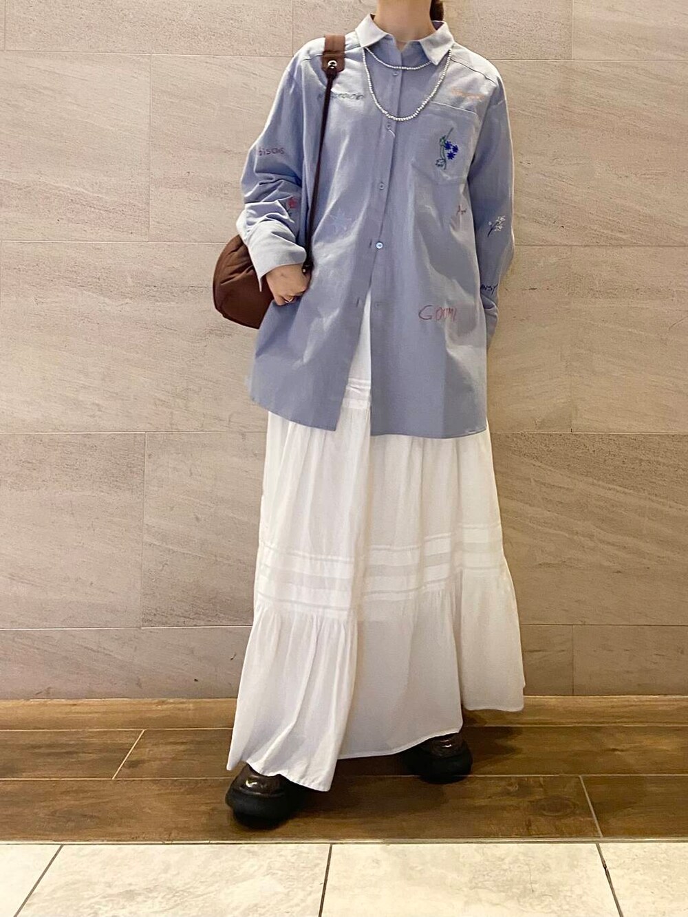 ブラウン系のローファー、ブラウン系のショルダーバッグ、ブルー系のシャツ/ブラウスを着用したレディースの冬コーディネートの2枚目の写真