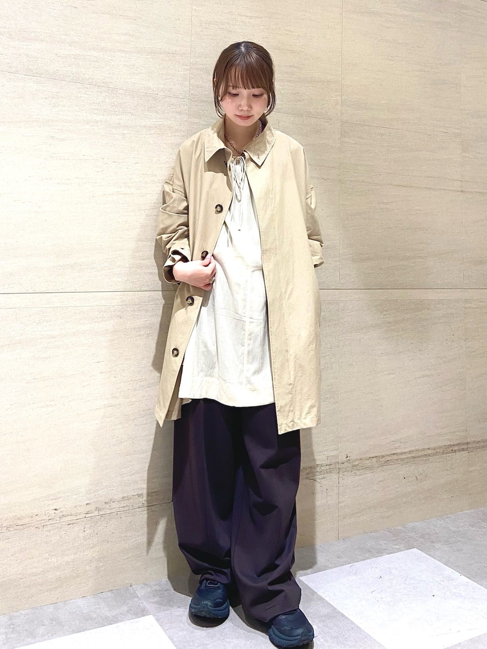 ベージュ系のステンカラーコート、ブラウン系のその他パンツ、ベージュ系のその他トップスを着用したレディースの春コーディネートの4枚目の写真