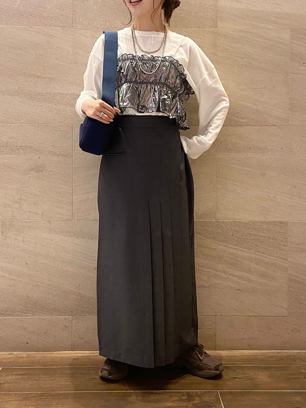 ブルー系のショルダーバッグ、グレー系のスカート、シルバー系のベストを着用したレディースの秋コーディネートの2枚目の写真