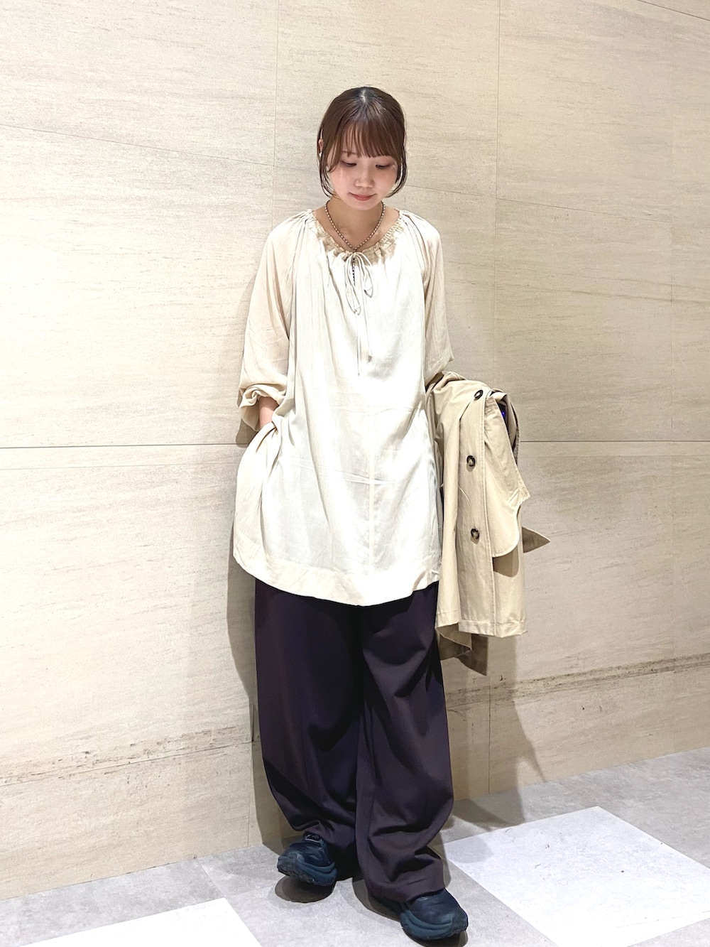 ベージュ系のステンカラーコート、ブラウン系のその他パンツ、ベージュ系のその他トップスを着用したレディースの春コーディネートの2枚目の写真