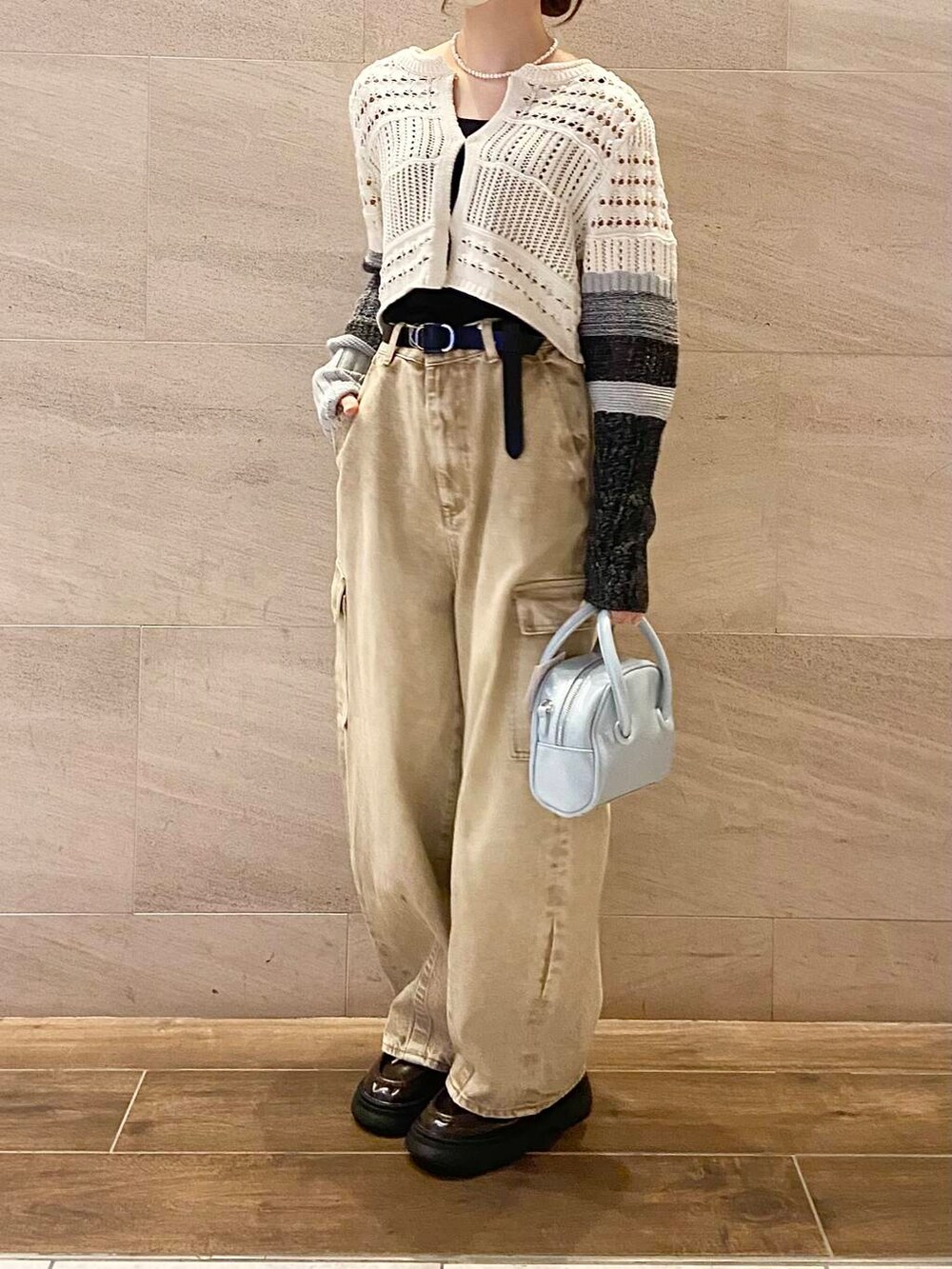ブルー系のボストンバッグ、ホワイト系のカーディガン/ボレロ、ベージュ系のデニムパンツを着用したレディースの春コーディネートの2枚目の写真
