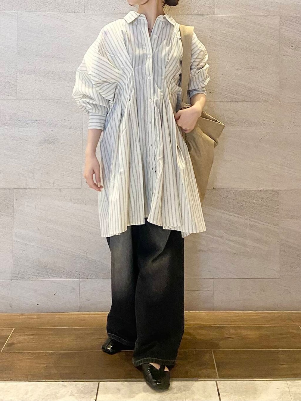 ブラック系のデニムパンツ、ベージュ系のワンピース、ベージュ系のショルダーバッグを着用したレディースの春コーディネートの2枚目の写真