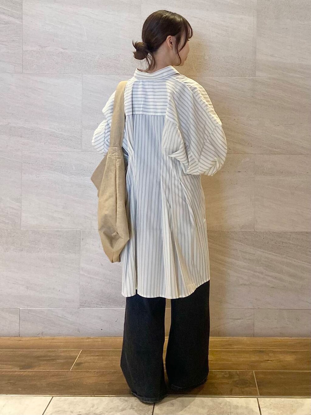 ブラック系のデニムパンツ、ベージュ系のワンピース、ベージュ系のショルダーバッグを着用したレディースの春コーディネートの4枚目の写真