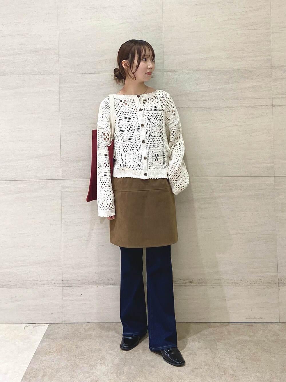 イエロー系のスカート、ベージュ系のカーディガン/ボレロ、レッド系のトートバッグを着用したレディースの秋コーディネートの2枚目の写真