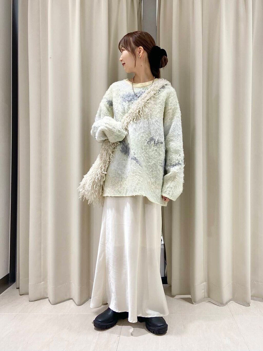 ブラック系のブーツ、ホワイト系のショルダーバッグ、ホワイト系のスカートを着用したレディースの冬コーディネートの2枚目の写真