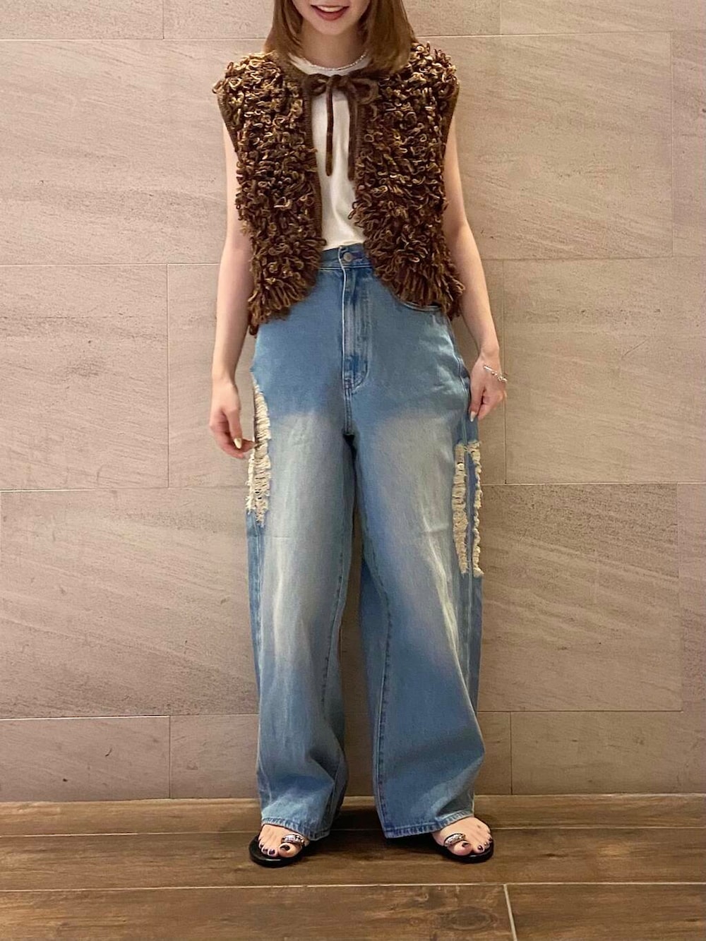 ブラウン系のベスト、ブルー系のデニムパンツ、ホワイト系のTシャツ/カットソーを着用したレディースの夏コーディネートの2枚目の写真