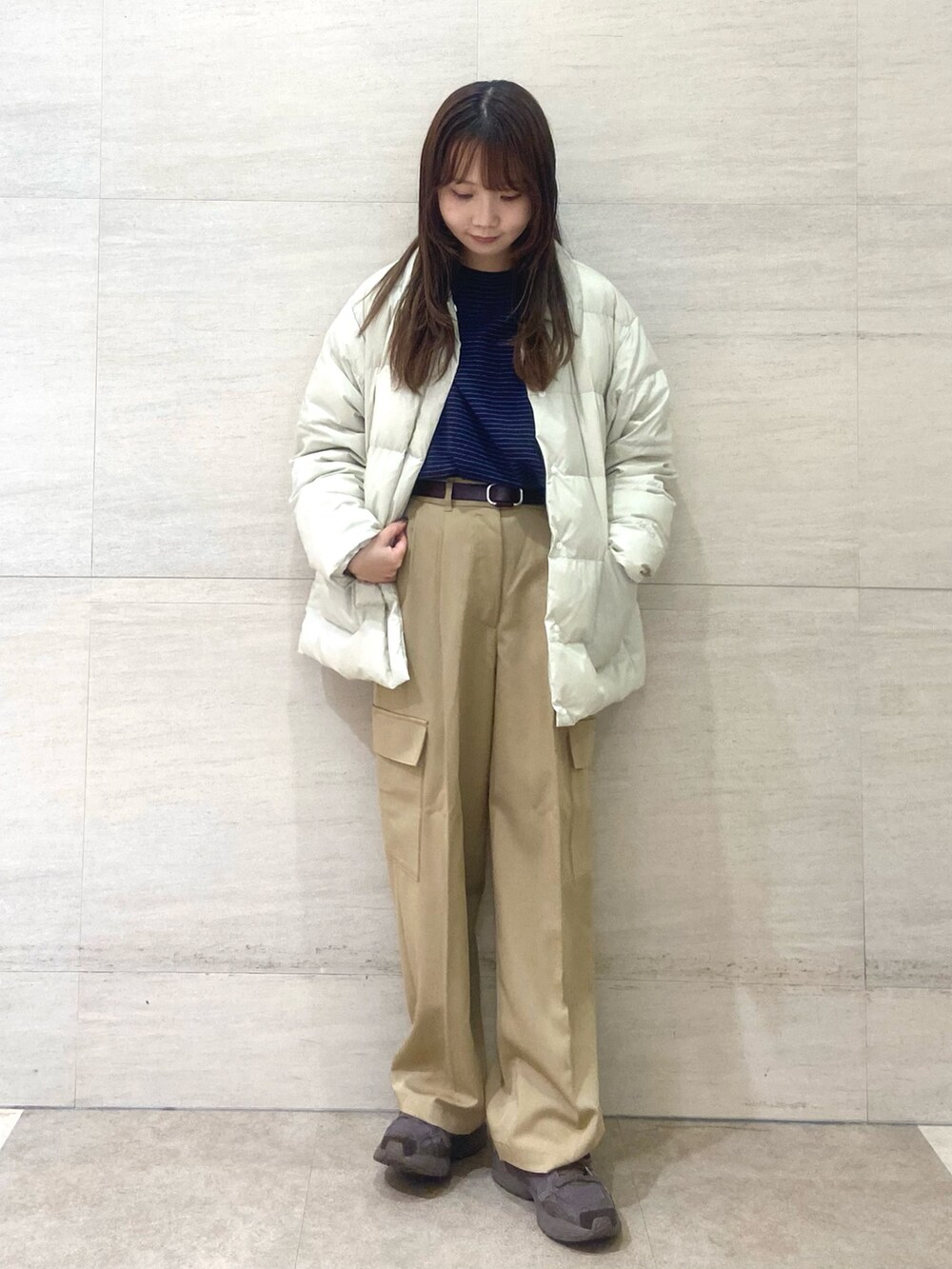 ホワイト系のダウンジャケット/コート、ブラウン系のニット/セーター、ベージュ系のその他パンツを着用したレディースの秋コーディネートの2枚目の写真