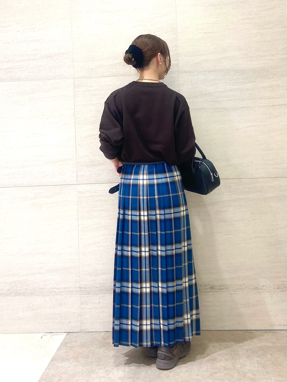 グリーン系のスカート、ブラウン系のニット/セーター、ブラック系のショルダーバッグを着用したレディースの秋コーディネートの3枚目の写真