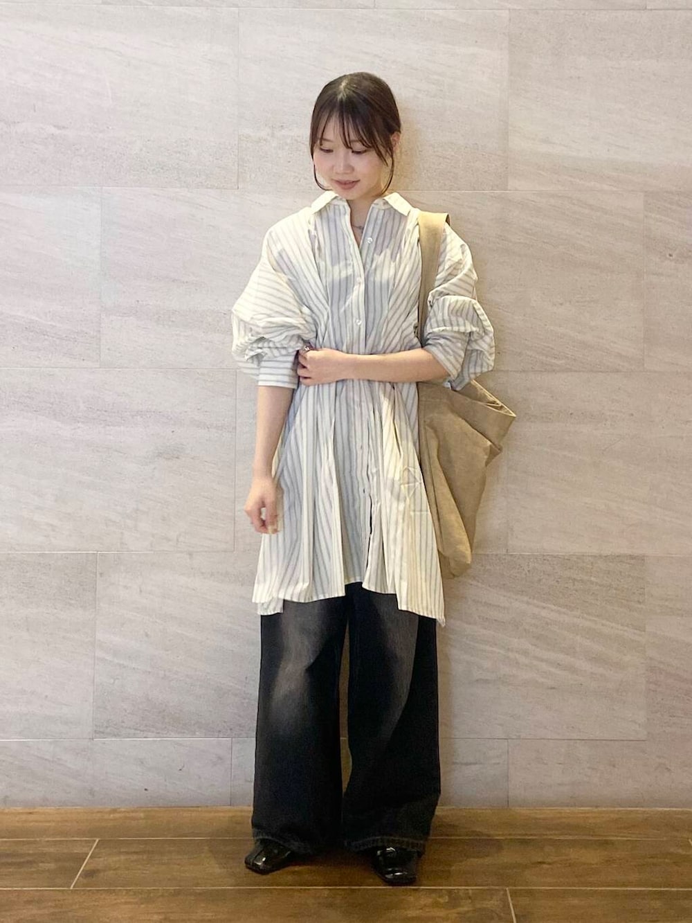 ブラック系のデニムパンツ、ベージュ系のワンピース、ベージュ系のショルダーバッグを着用したレディースの春コーディネートの6枚目の写真