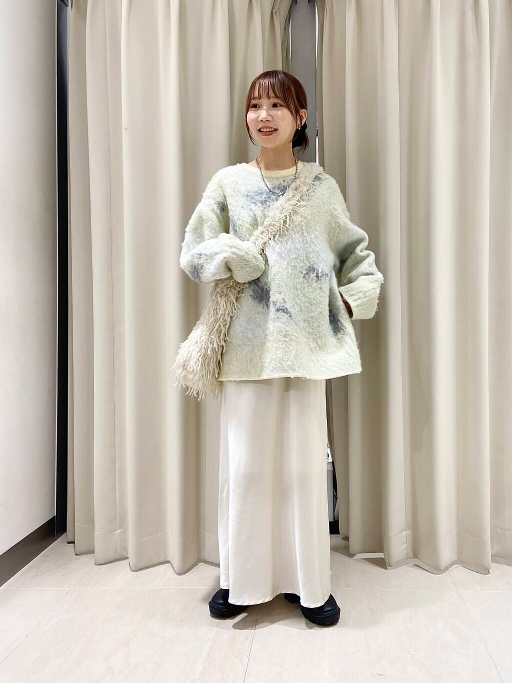 ブラック系のブーツ、ホワイト系のショルダーバッグ、ホワイト系のスカートを着用したレディースの冬コーディネートの4枚目の写真