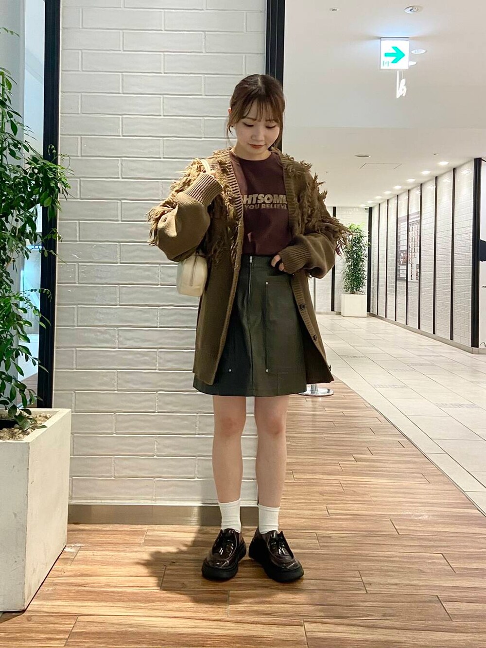 ブラウン系のローファー、グリーン系のカーディガン/ボレロ、ブラウン系のTシャツ/カットソーを着用したレディースの秋コーディネートの5枚目の写真