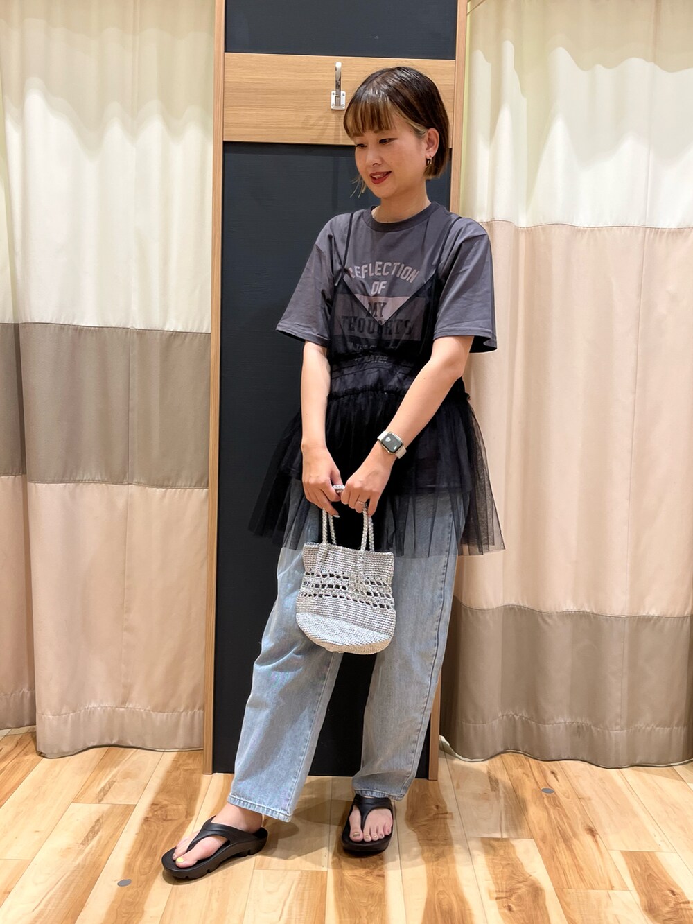 グレー系のトップス、ブルー系のデニムパンツ、シルバー系のバッグを着用したレディースの夏コーディネートの2枚目の写真